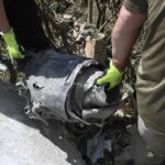 Ukrainian experts carry the remains of a rocket at the site of a missile attack on a five-story residential building in kyiv, Ukraine