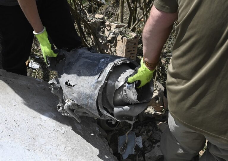 Ukrainian experts carry the remains of a rocket at the site of a missile attack on a five-story residential building in kyiv, Ukraine