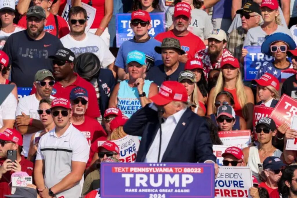 Trump puts his hand to his ear after hearing the shots